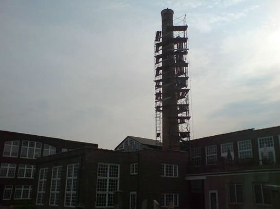 A brick building with a chimney and stairs in front of it