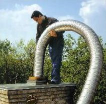 A man is working on a chimney with a hose attached to it.