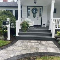 A white house with a porch , stairs and a mailbox.