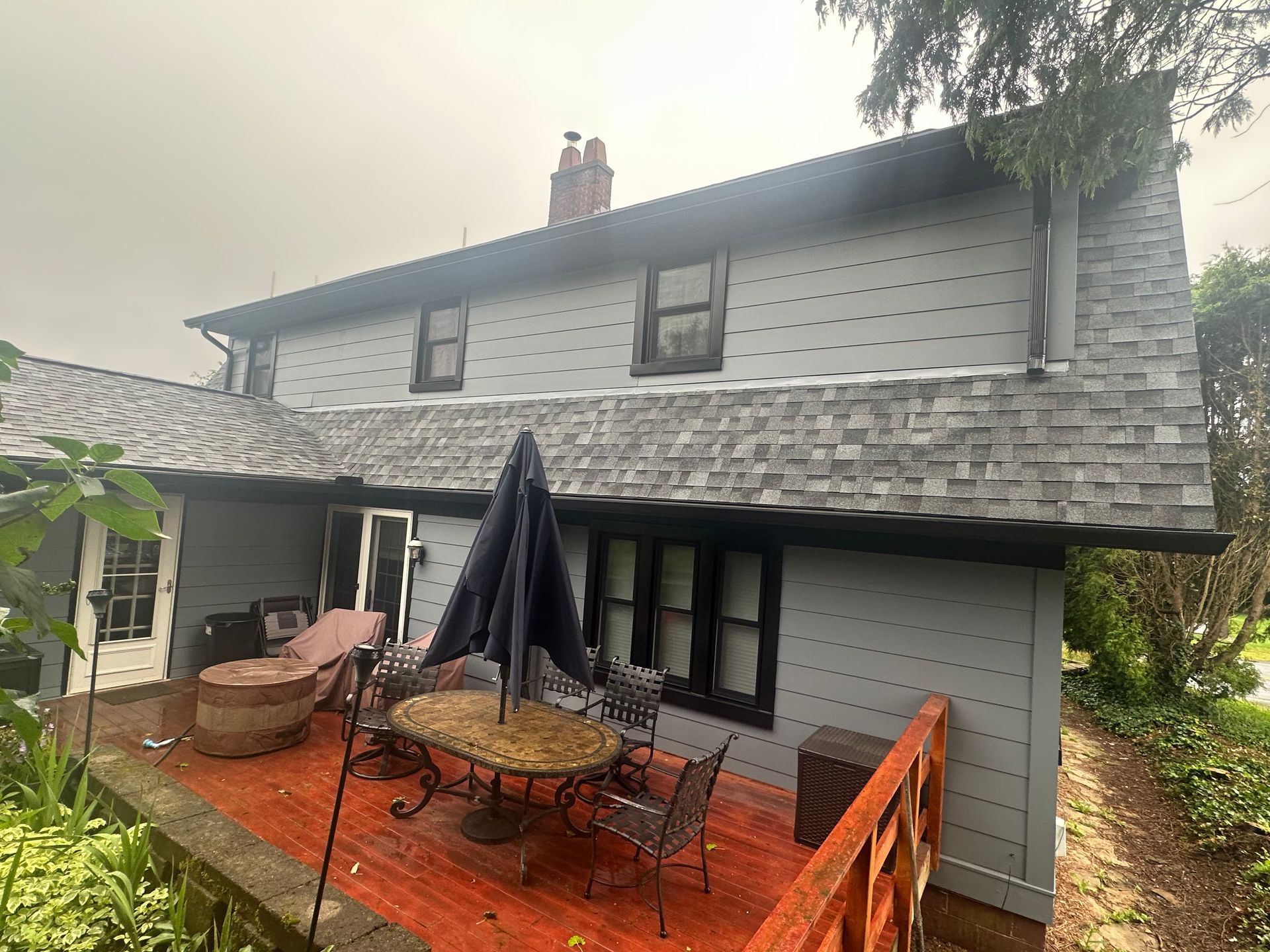 A large house with a patio with a table and chairs and umbrellas.