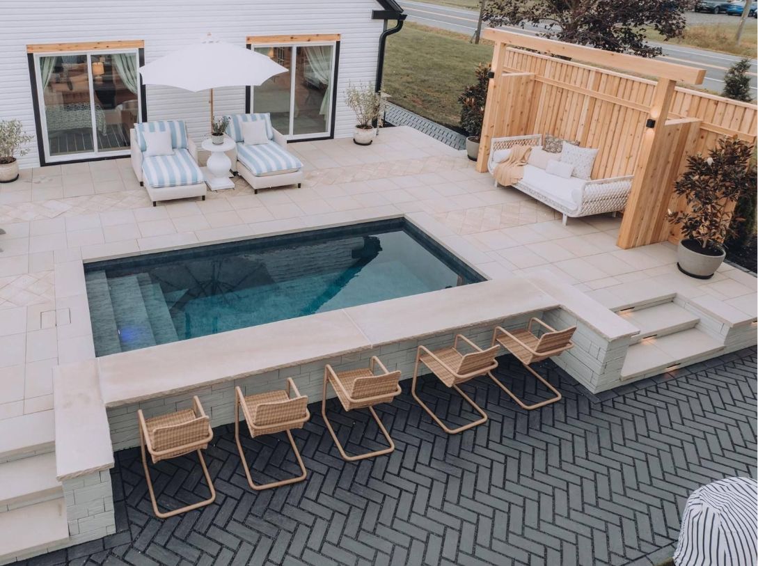 Modern backyard patio with pool, lounge chairs, white seating, and wooden privacy screens