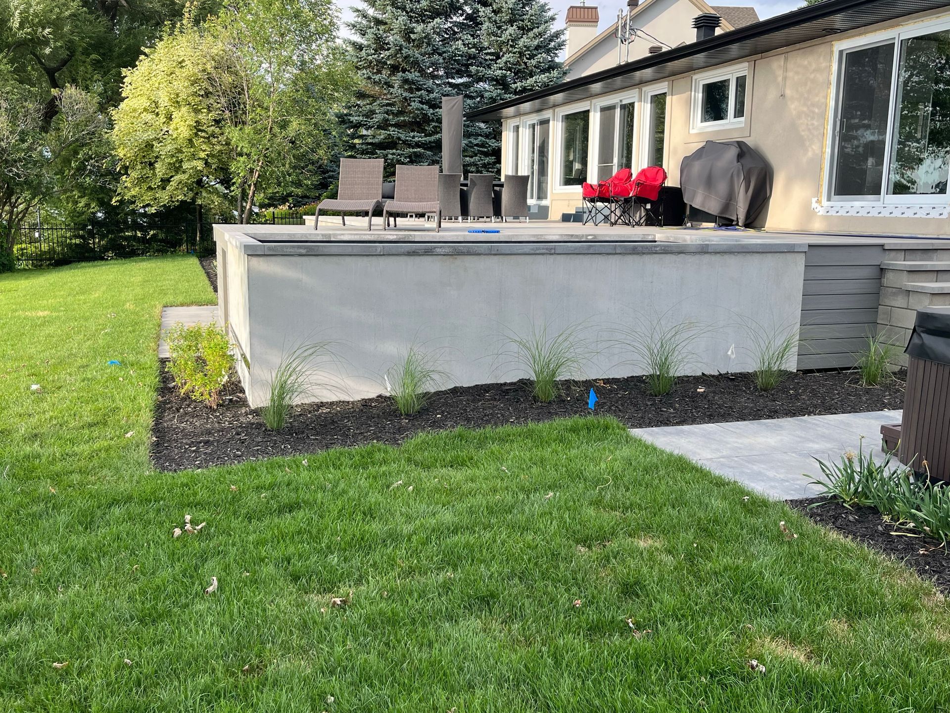 Backyard patio with stone retaining wall, lawn, and outdoor seating beside a house