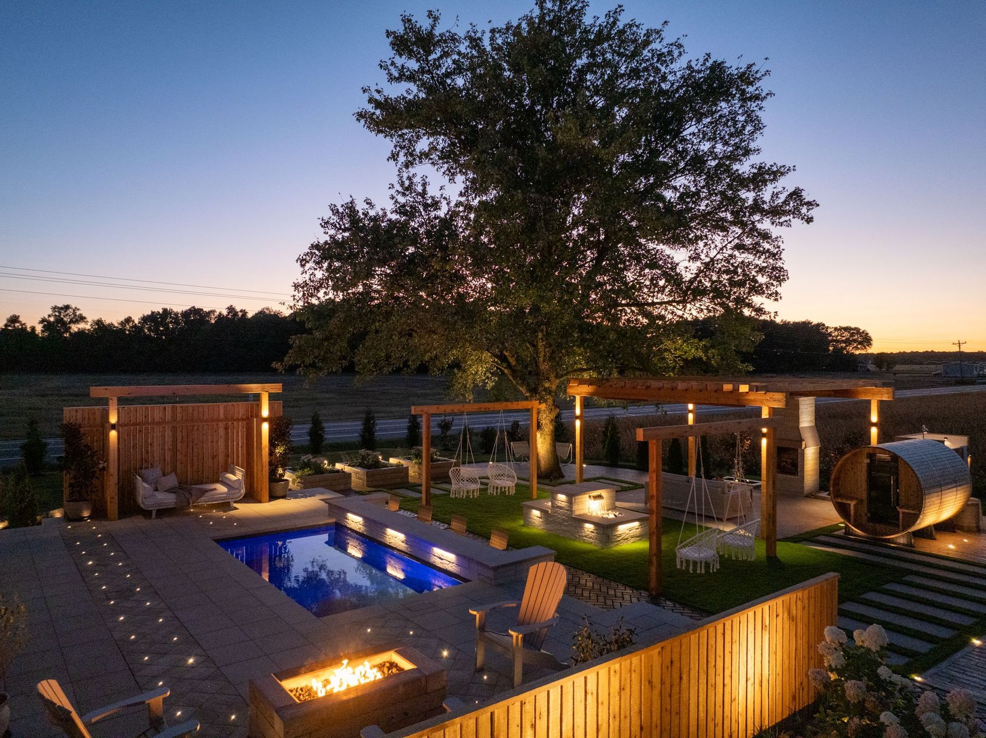 Empty swimming pool with beige stone decking and a white house in the background. Blue tile trim.