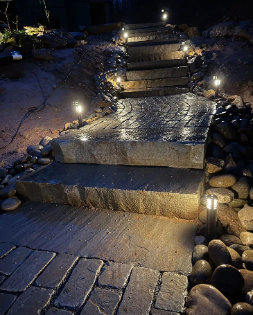Stone steps with path lit by small lights at night.