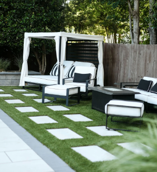Outdoor patio with white and black furniture, green grass, and a cabana.