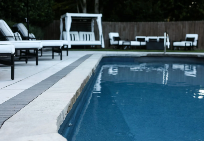 Poolside scene with pool, lounge chairs, seating, and a cabana.