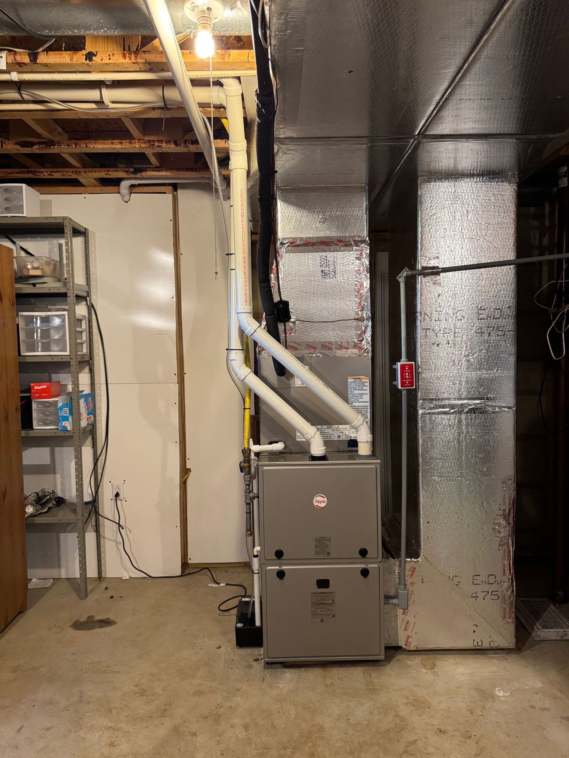 Basement furnace and HVAC ductwork beside insulated metal venting and storage shelves