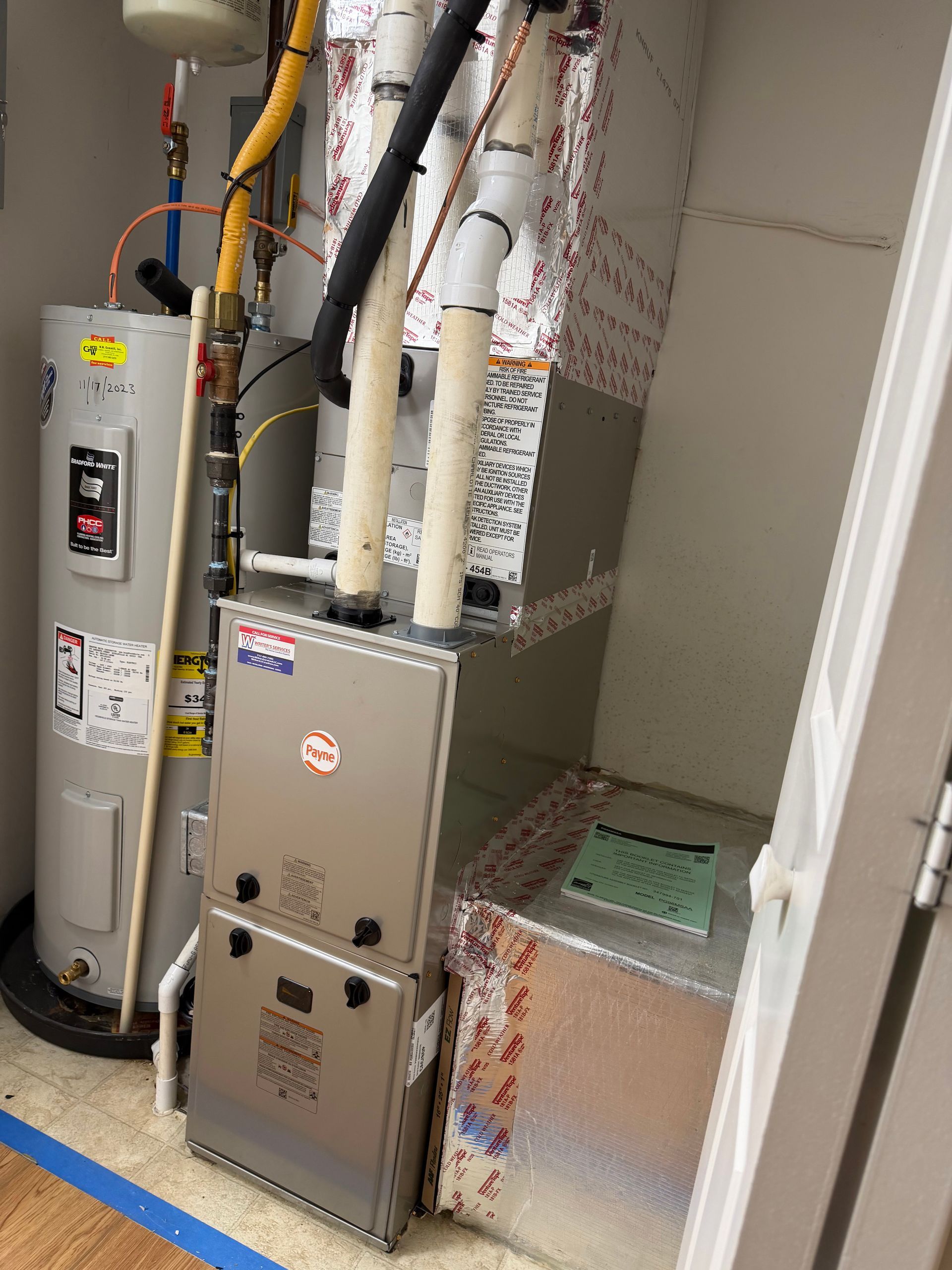 HVAC and water heater equipment in a utility closet with insulated pipes and ductwork