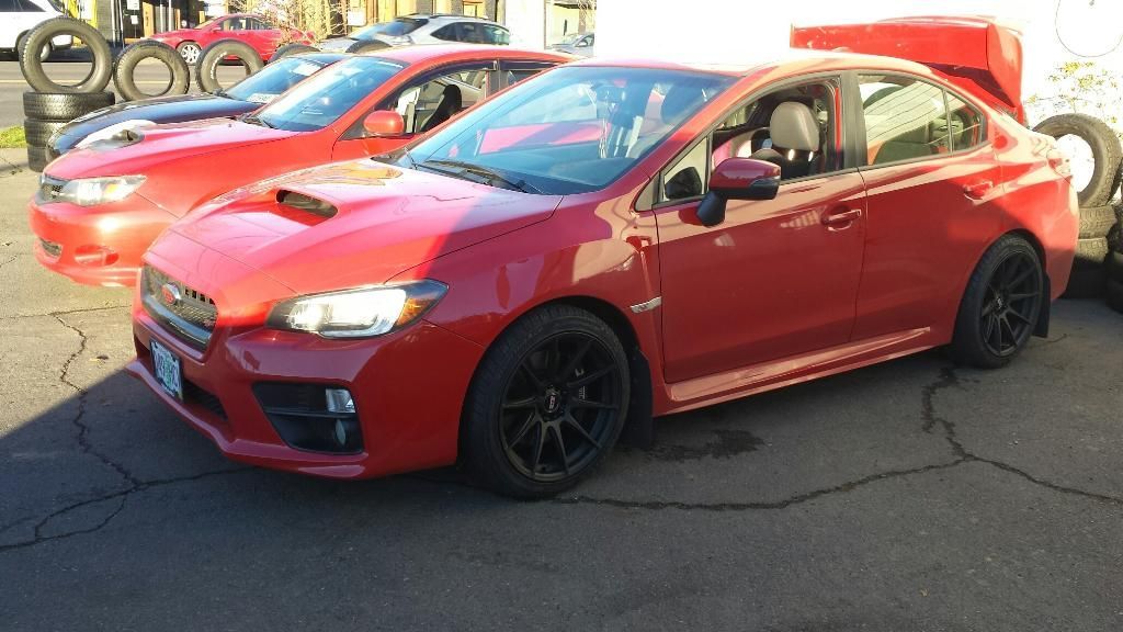 Two red cars are parked next to each other in a parking lot.