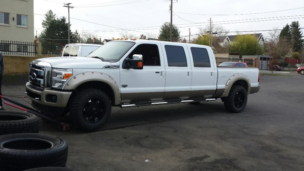 A white truck is parked in a parking lot next to a pile of tires.