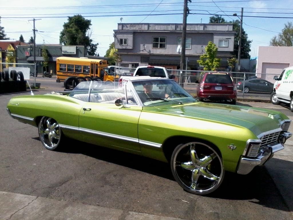 A green car is parked in front of a yellow school bus