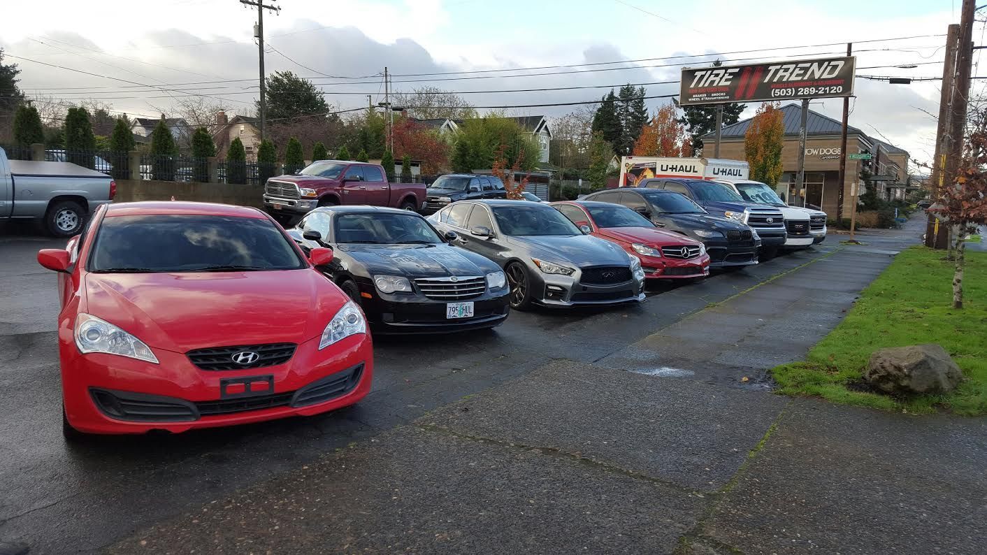 A row of cars are parked in front of a car dealership.