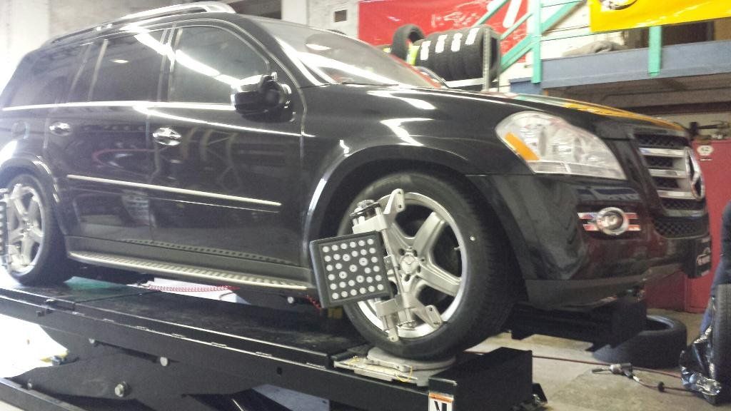A black suv is sitting on a lift in a garage.