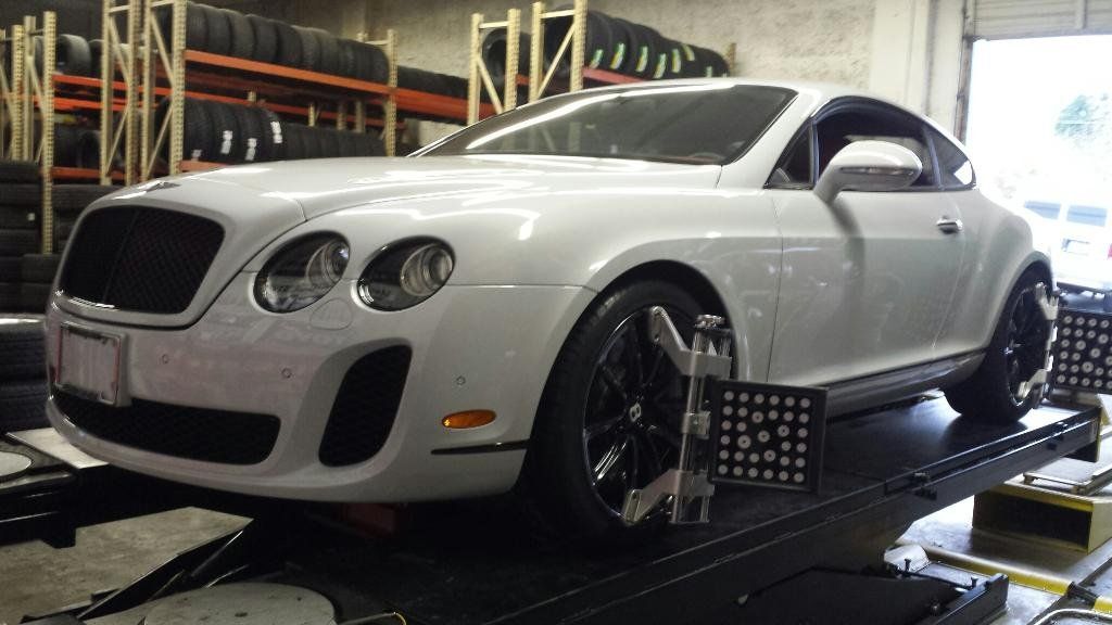 A white bentley is sitting on a lift in a garage.