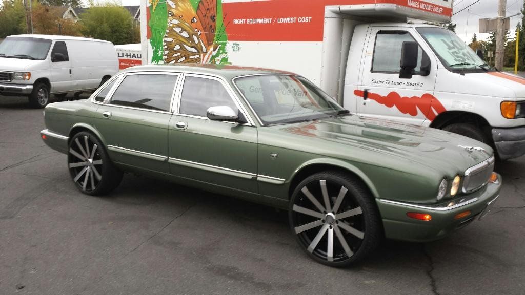 A green car is parked next to a white van