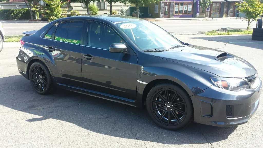 A black subaru impreza is parked in a parking lot.