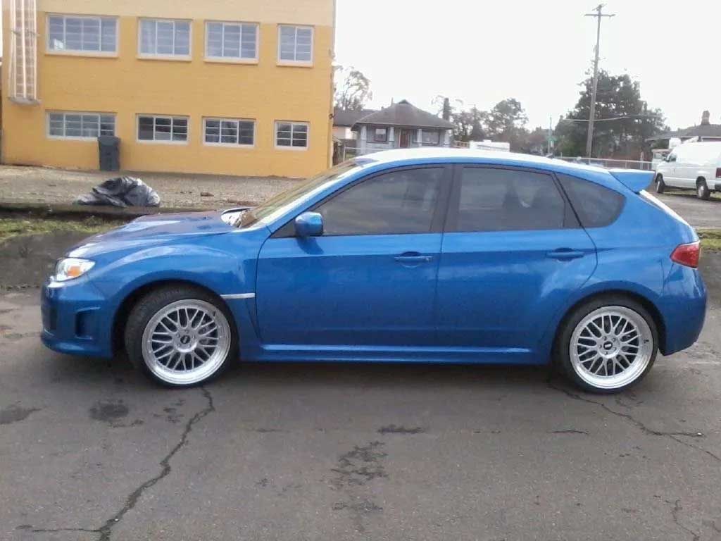 A blue car is parked in front of a yellow building