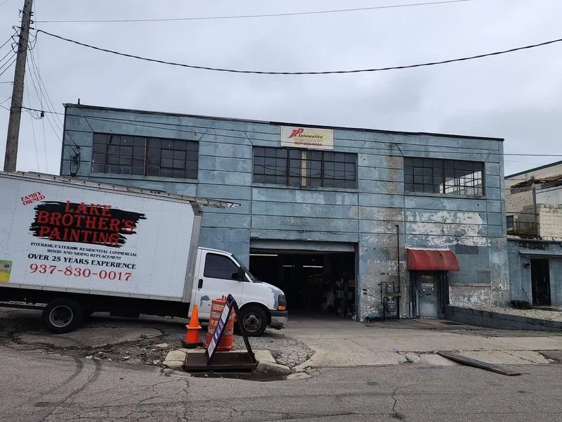 Box truck outside a two-story industrial building with an open garage and a sign for Brothers Painting.