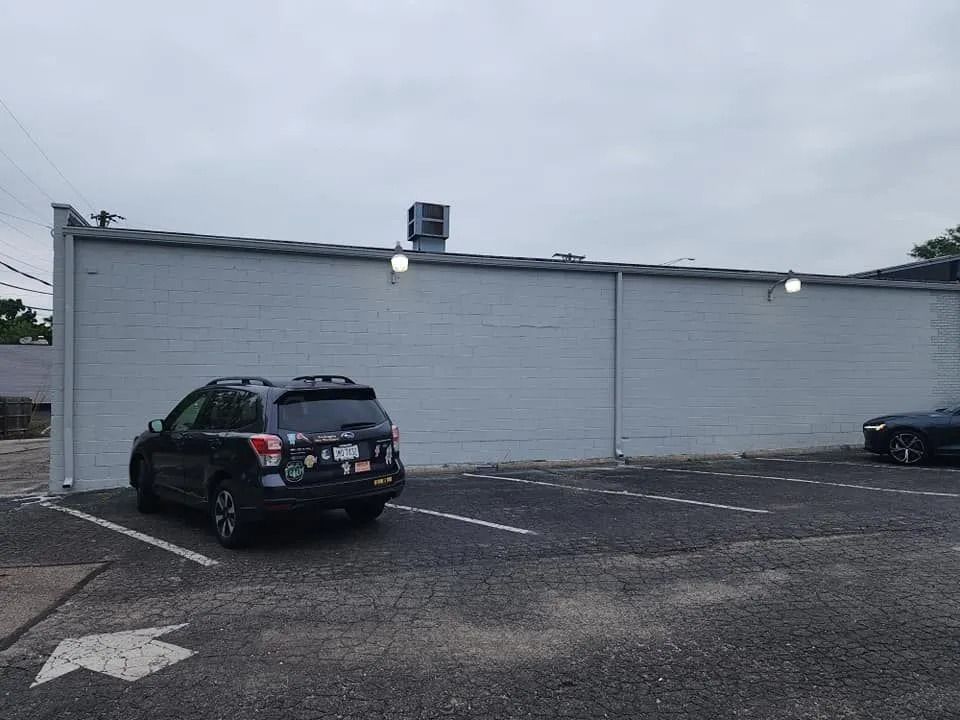 Parking lot beside a white building with two parked cars under an overcast sky