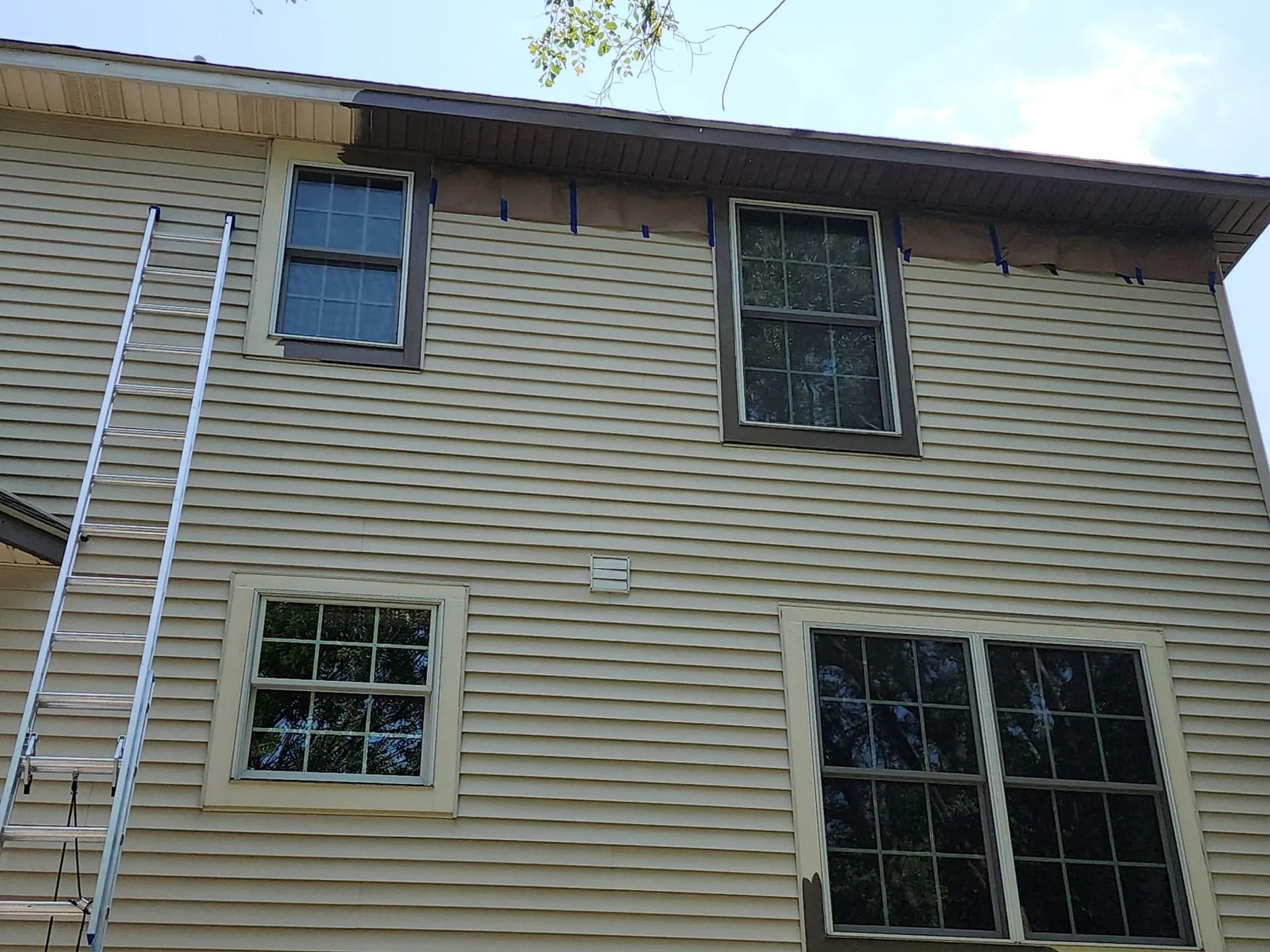 Exterior of a beige house with several windows and white trim viewed from below