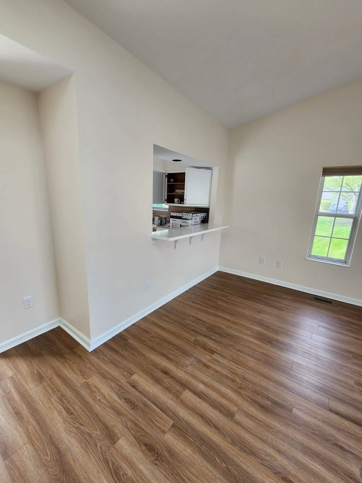 Empty room with wood floors, white walls, a pass-through window, and a windowed door.