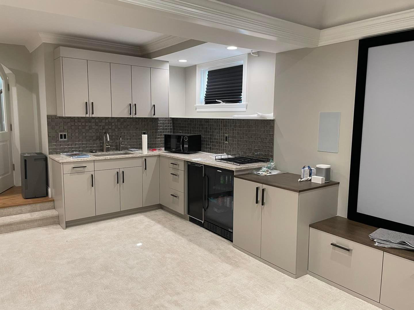 A kitchen with white cabinets and a projector screen.