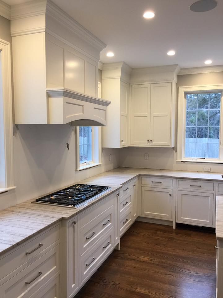 A kitchen with white cabinets and a stove top oven.