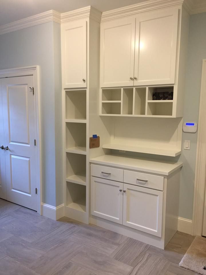 A room with white cabinets and shelves and a door.