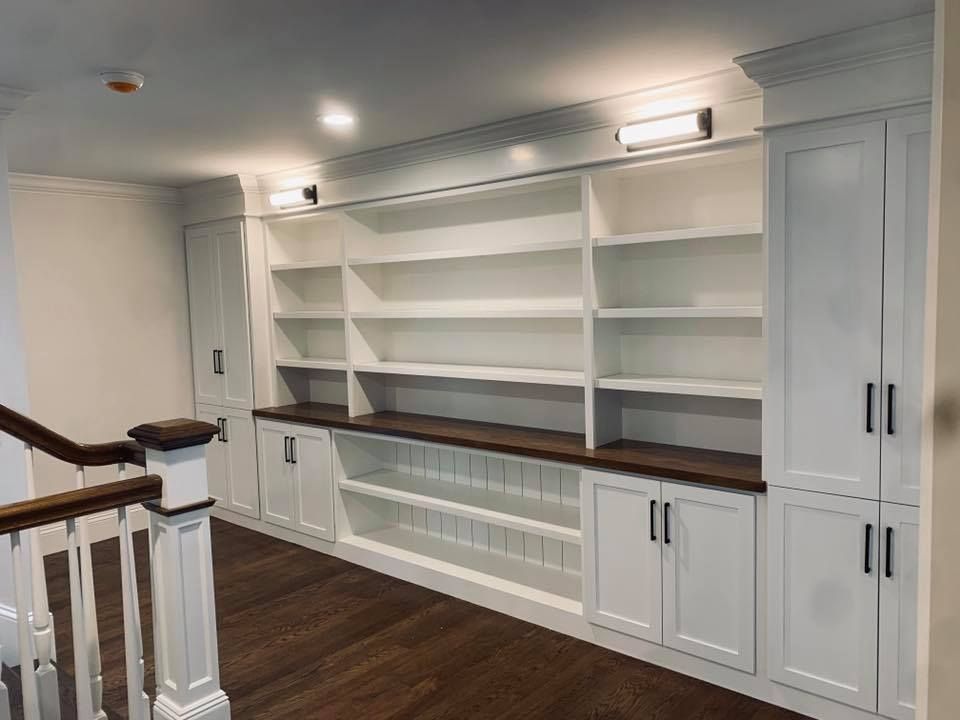 A room with a staircase and lots of shelves and cabinets.