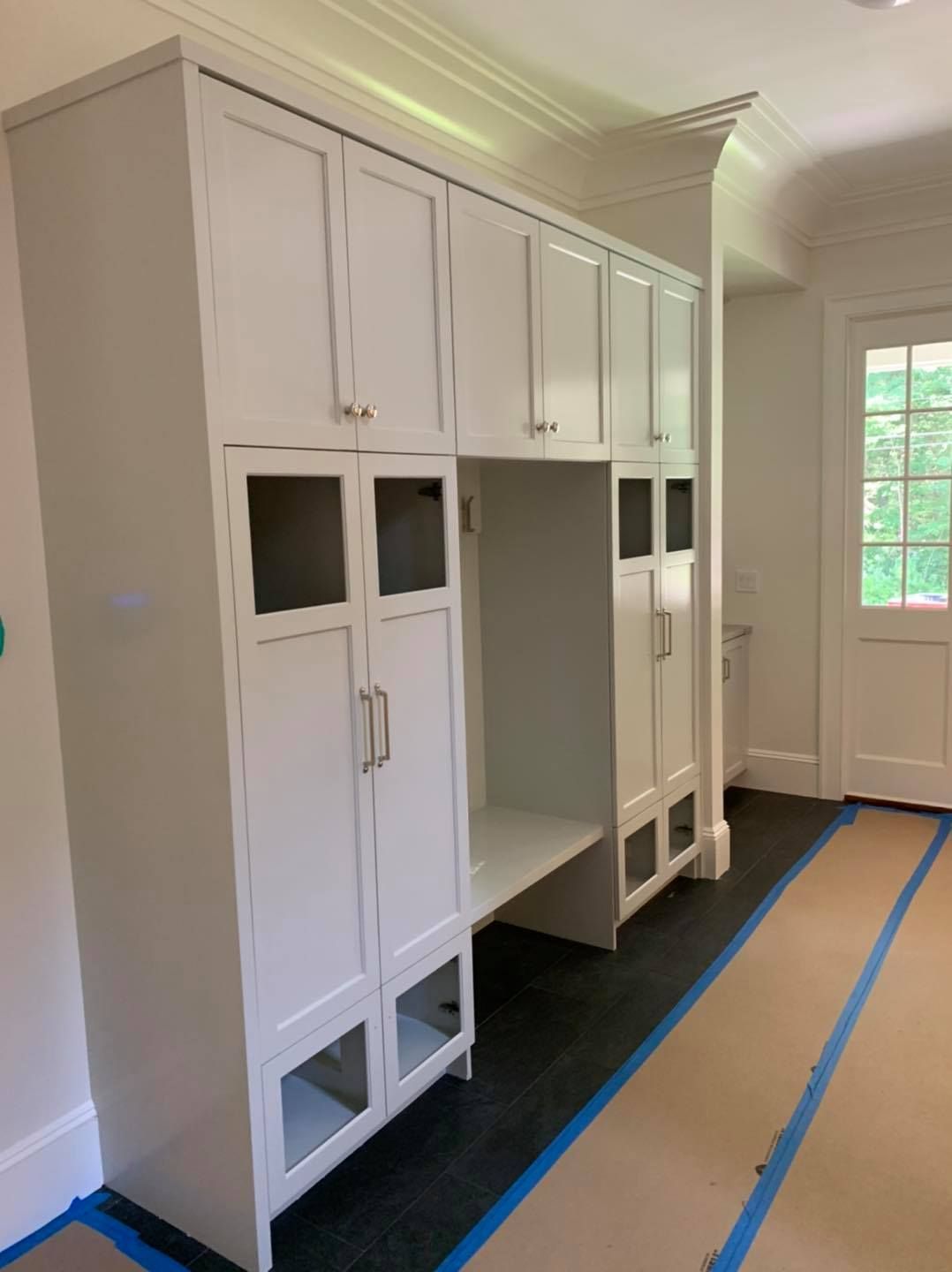 A hallway with white cabinets and blue tape on the floor
