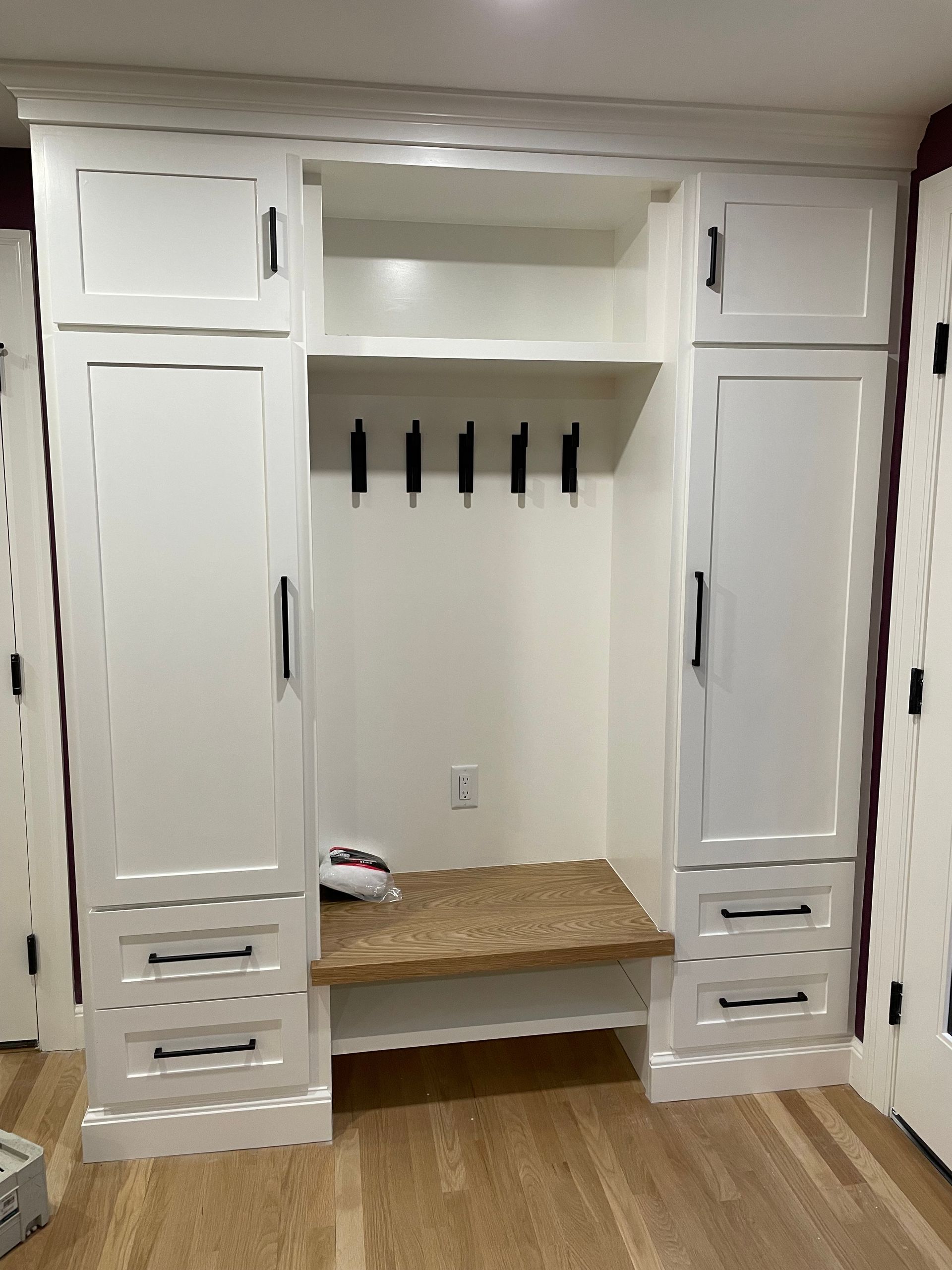 A room with white cabinets , drawers, and a bench.