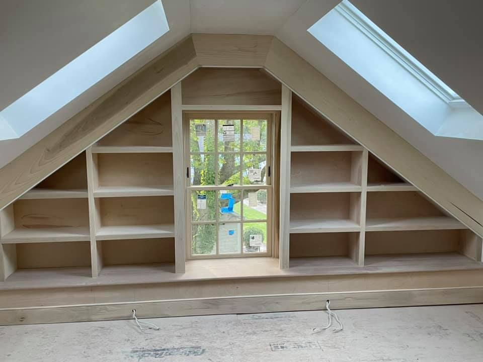 A room with a window and shelves in the attic.