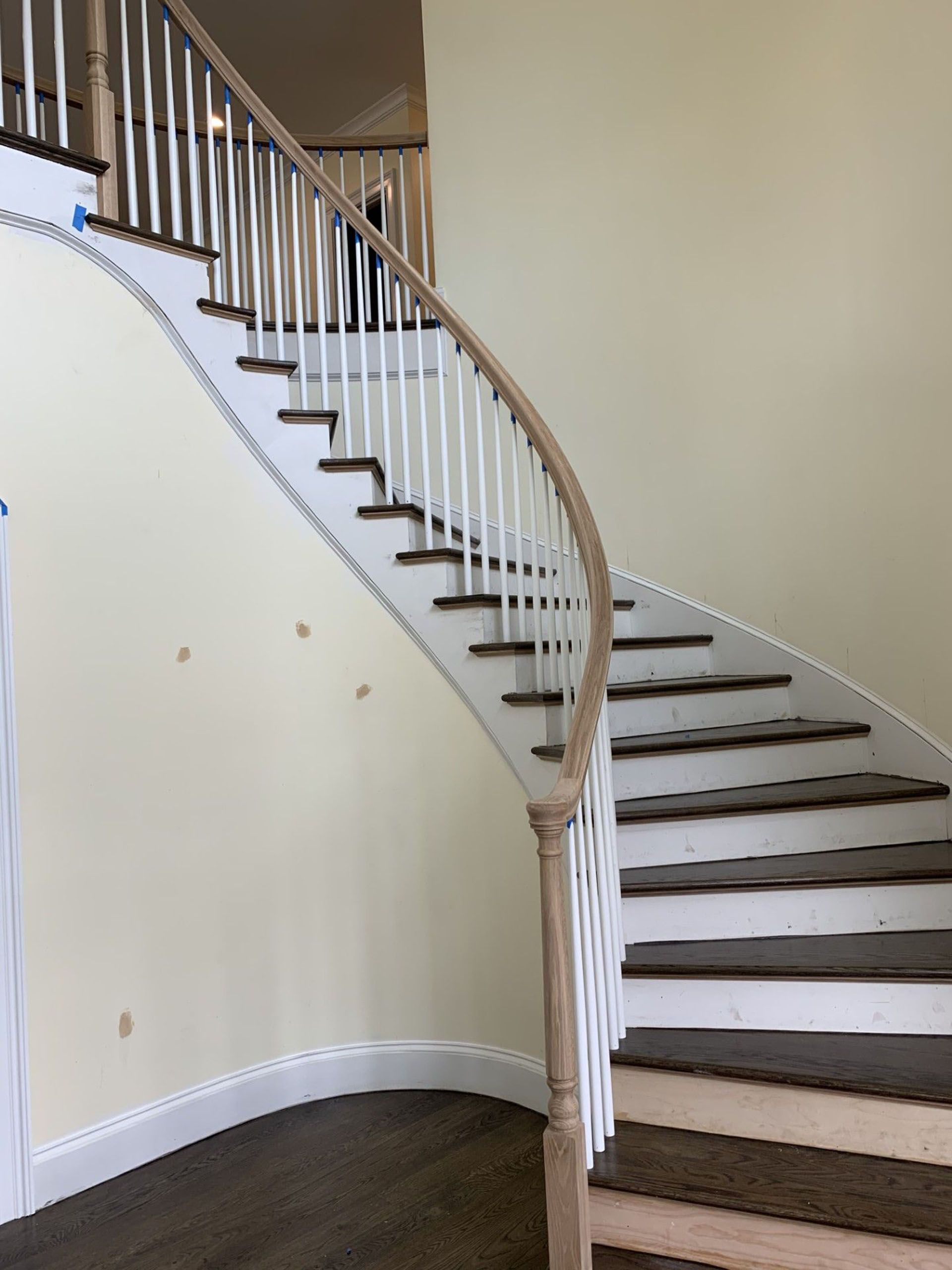 A curved staircase with white railings and brown steps in a room.