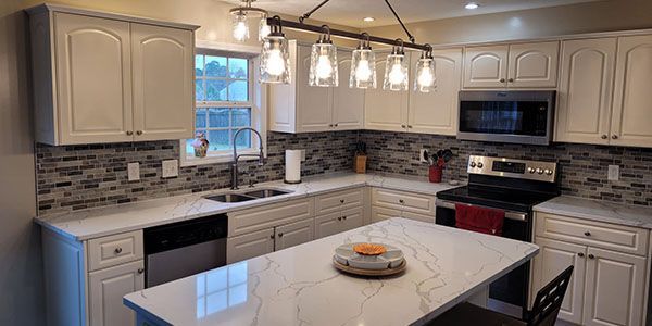A kitchen with white cabinets , granite counter tops , stainless steel appliances and a large island.