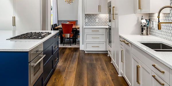A kitchen with white cabinets , stainless steel appliances , a sink and a stove.