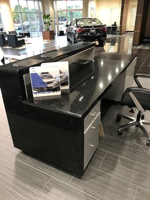 A car is parked behind a desk in a showroom.