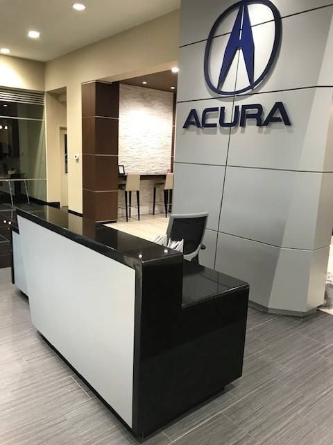 A black and white desk in front of a sign that says acura