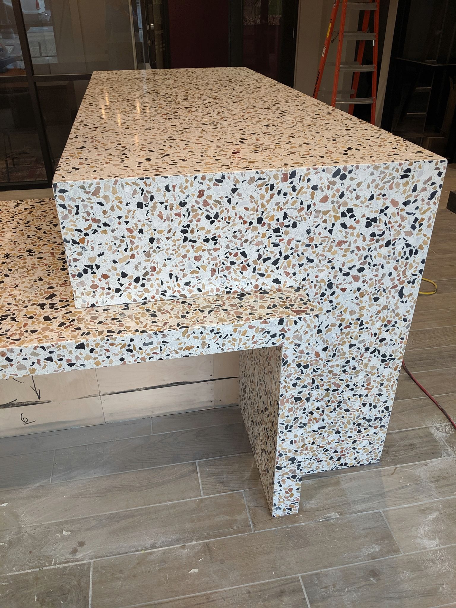 A counter top made of terrazzo is sitting on a tiled floor.