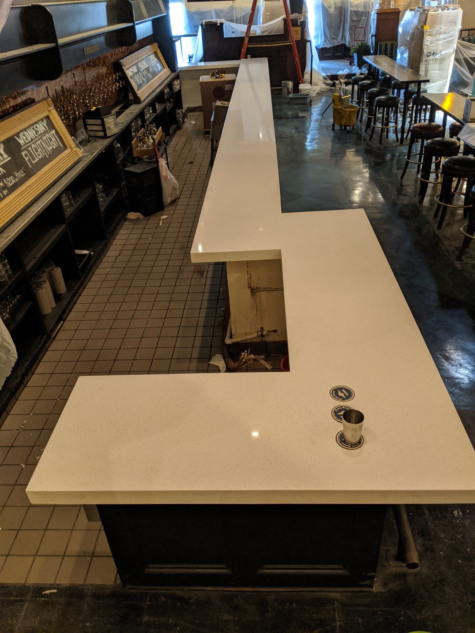 A long white counter in a restaurant with a ladder in the background.