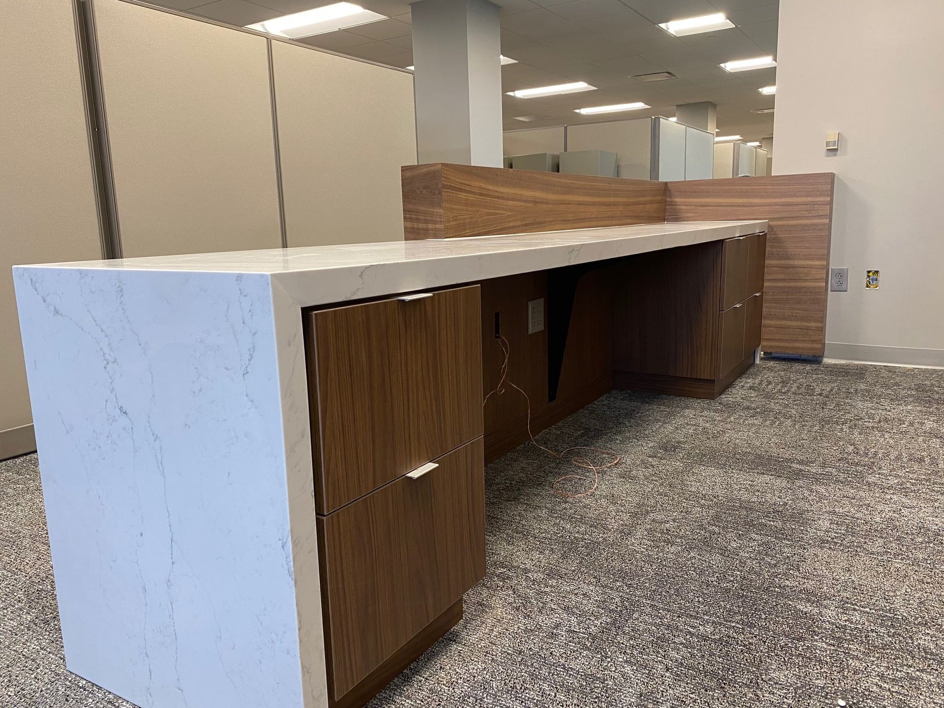 A long desk with drawers and a marble top in a room.