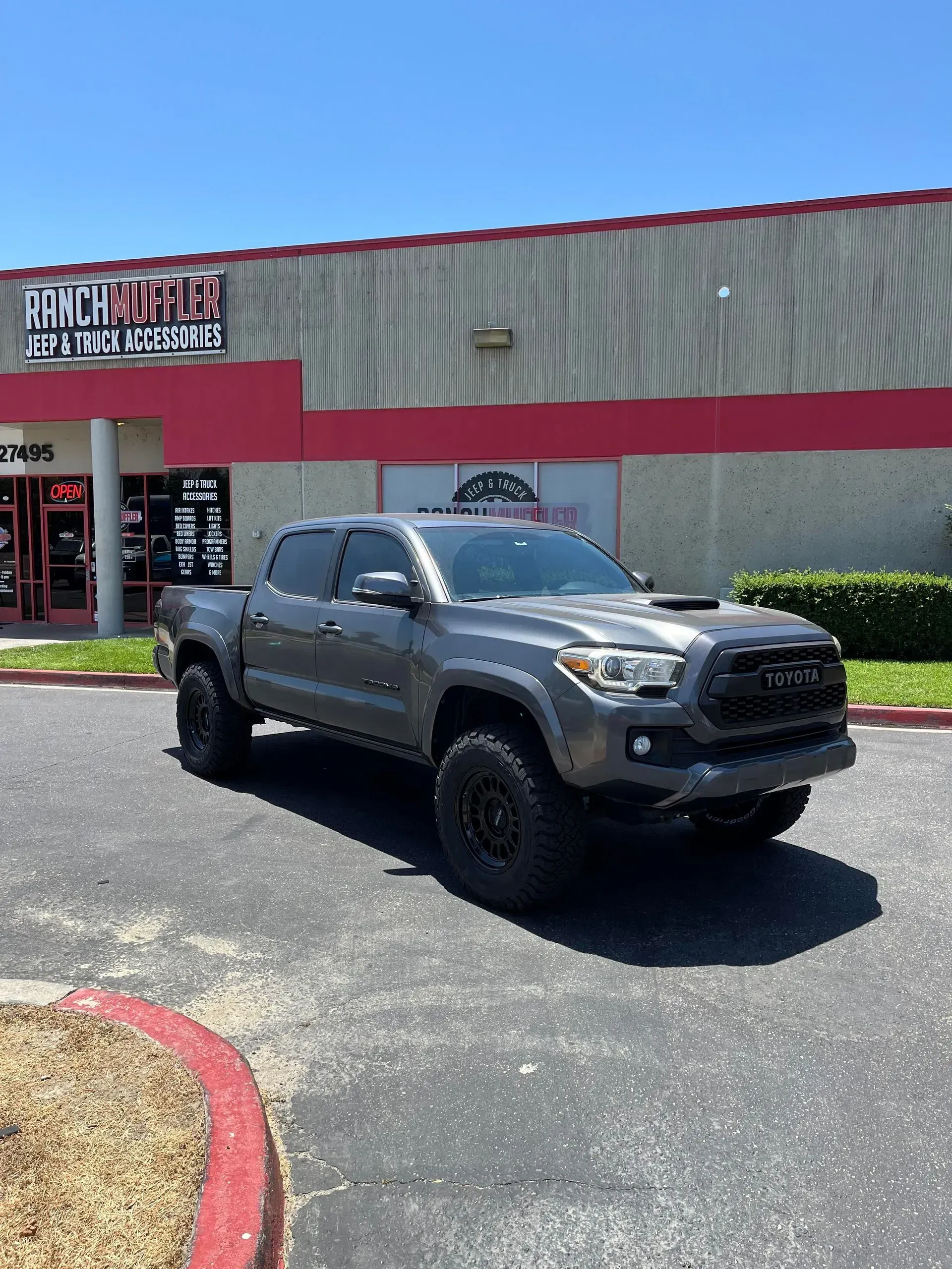 Gray Toyota Tacoma parked in front of a building with red and white signage.