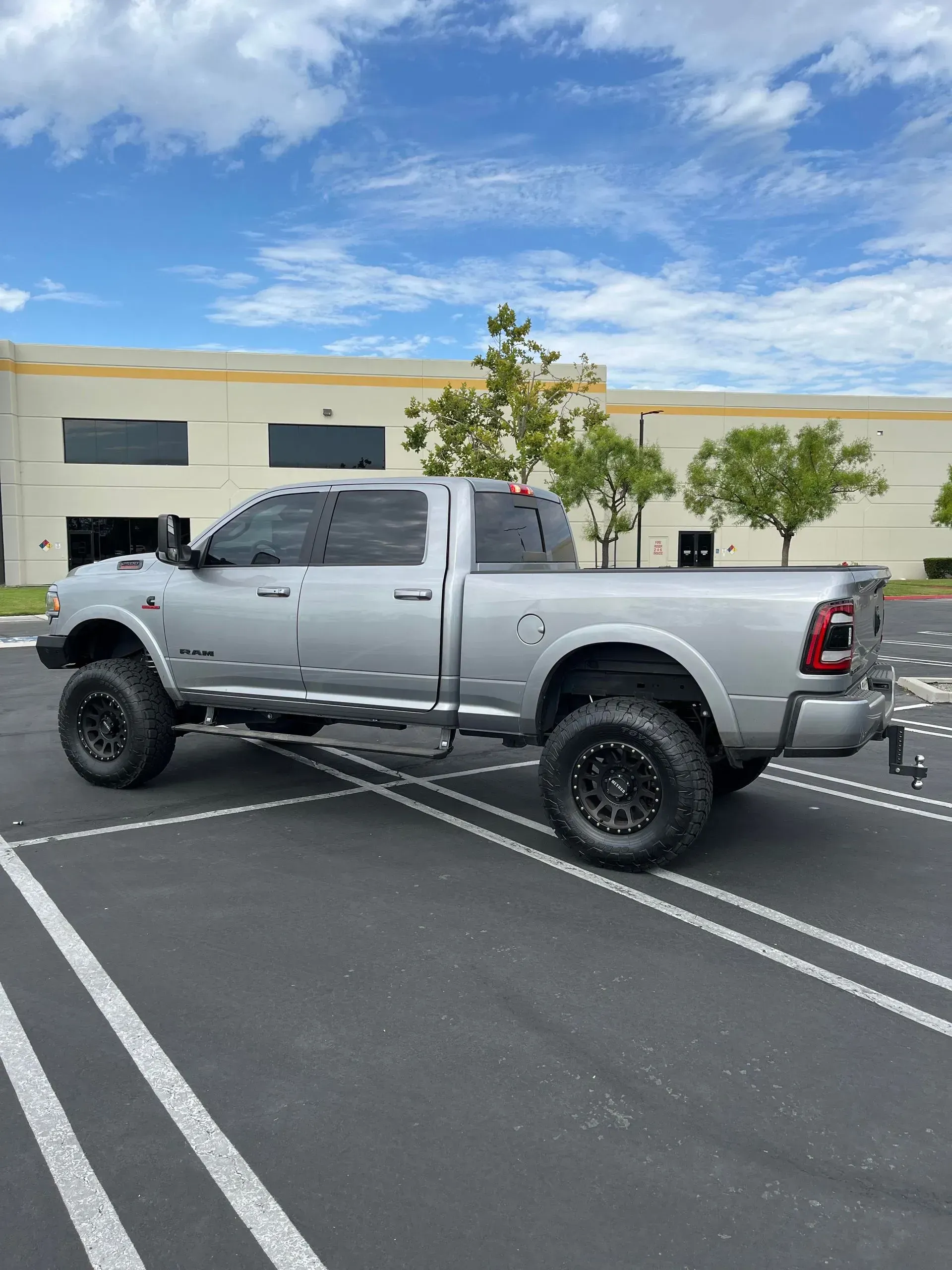 Silver Ram pickup truck parked in front of a building on a sunny day.