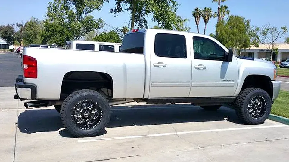 Silver pickup truck parked outside, with black wheels and a lifted suspension.