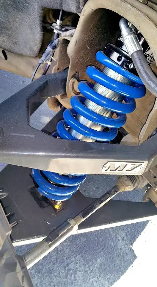 Blue coil-over shock absorber installed on a vehicle's suspension system.