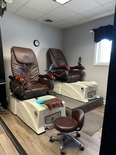 Two brown pedicure massage chairs with built-in foot tubs and a rolling technician stool in a neutral-toned spa room.
