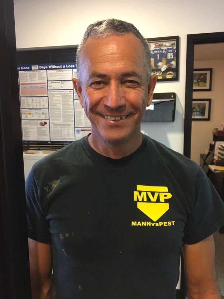 A smiling person wears a navy blue t-shirt with a yellow 