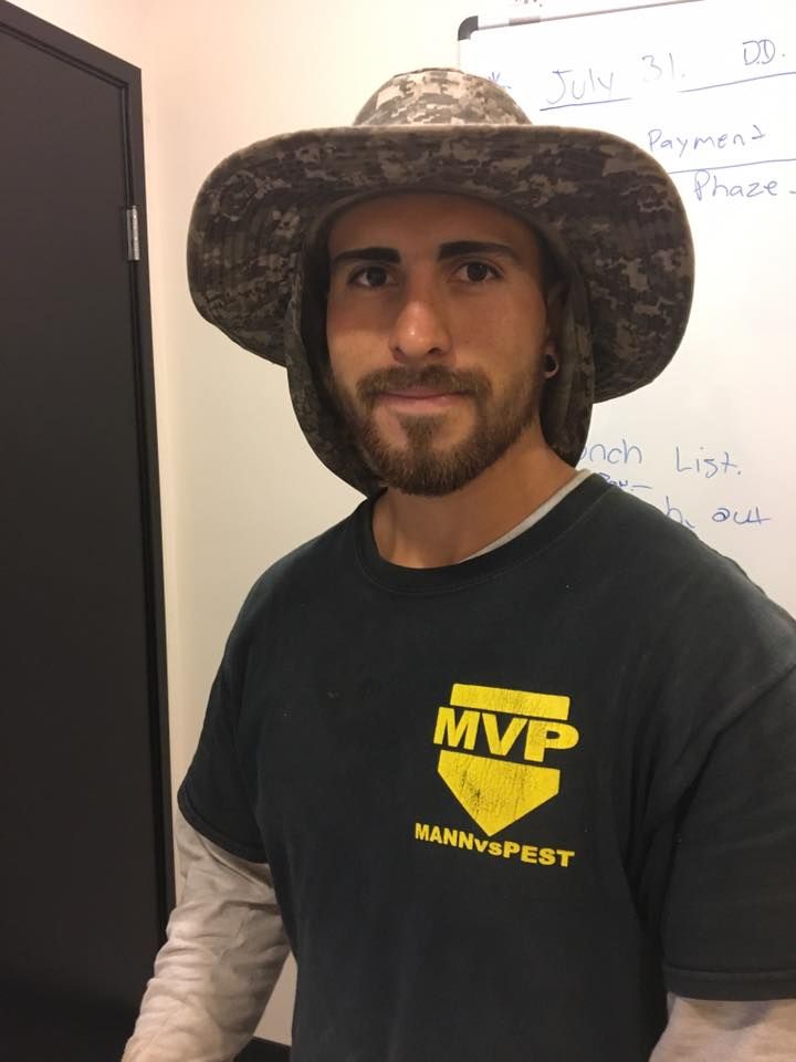 A person wearing a wide-brimmed camo hat and a black T-shirt with a yellow 