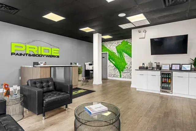 Interior of Pride Paint & Bodyworks, waiting area. Black leather seating, reception desk, green logo on wall.