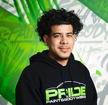 Man with curly hair in a black hoodie smiles.  