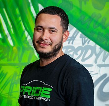 Man wearing black shirt smiles in front of green and white graffiti.